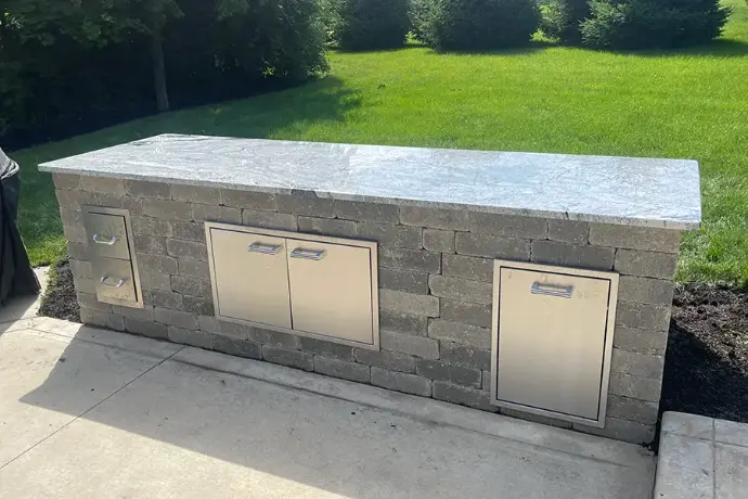 Luxury outdoor kitchen island with expansive white granite countertops and stainless steel storage