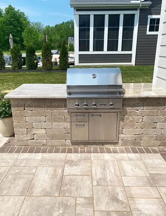 outdoor built in grill station built with tan wall stone on a custom paver patio